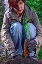 Beautiful woman holds sapling Climatis in her hands. Gardener looks at the plant seedling with roots