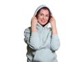 Beautiful woman in a hoodie covers her head with a hood and smiles. Studio shot, medium shot, isolated