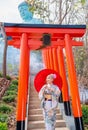 Beautiful woman with Japanese style dress hold red umbrella and stand on base stairs with red arched entrance in area of tourist Royalty Free Stock Photo