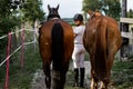 Beautiful woman leads horses from training session on summer evening.Photo from the back. Athlete turns around and smiles. Sports