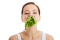 Beautiful woman with leaf of lettuce in mouth. Royalty Free Stock Photo