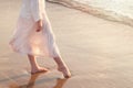 Beautiful woman legs on the beach with sea surf at sunset. Romanc step on surf Royalty Free Stock Photo