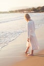 Beautiful woman legs on the beach with sea surf at sunset. Romanc step on surf Royalty Free Stock Photo