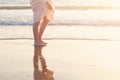 Beautiful woman legs on the beach with sea surf at sunset. Romanc step on surf Royalty Free Stock Photo