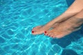 Beautiful women legs in blue water. Beautiful sexy female feet relaxing by the swimming pool. Summer background for traveling Royalty Free Stock Photo