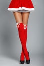 Beautiful woman legs dressed in christmas red dress and socks. Slender legs Royalty Free Stock Photo