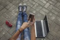 Beautiful woman legs with phone, laptop, glasses on the sidewalk