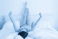 Woman stretching in bed with legs raised up high in bedroom Royalty Free Stock Photo