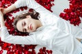 a beautiful woman lies in the flowers of the petals of red roses Royalty Free Stock Photo