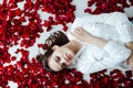 a beautiful woman lies in the flowers of the petals of red roses Royalty Free Stock Photo