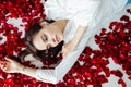 a beautiful woman lies in the flowers of the petals of red roses Royalty Free Stock Photo