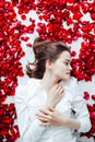 a beautiful woman lies in the flowers of the petals of red roses Royalty Free Stock Photo