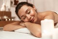 Beautiful woman lies in massage room in spa over candles. Royalty Free Stock Photo