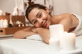 Beautiful woman lies in massage room in spa over candles. Royalty Free Stock Photo