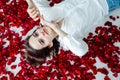 a beautiful woman lies in the petals of red rose flowers Royalty Free Stock Photo
