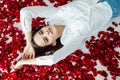 a beautiful woman lies in the petals of red rose flowers Royalty Free Stock Photo