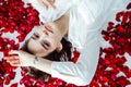 beautiful woman lies among the red petals of rose flowers Royalty Free Stock Photo