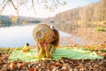 A beautiful woman lies on a yellow leaf with an amazing view of the lake and mountains and covers her face with a straw hat. A