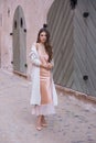 A beautiful woman in a light summer gown on the background of an old town.