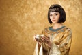 Beautiful woman like Egyptian Queen Cleopatra with cup on golden background