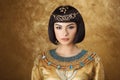 Beautiful woman like Egyptian Queen Cleopatra on golden background Royalty Free Stock Photo