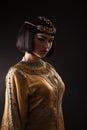 Beautiful woman like Egyptian Queen Cleopatra with serius face on black background.