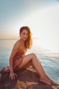 Beautiful woman in lingerie posing on a coastal cliff. Sea and sunset in the background. Vertical orientation Royalty Free Stock Photo