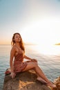 Beautiful woman in lingerie posing on a coastal cliff. Sea and sunset in the background. Vertical orientation. Proud posture Royalty Free Stock Photo