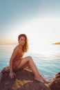 Beautiful woman in lingerie posing on a coastal cliff. Sea and sunset in the background. Vertical orientation. Wild look Royalty Free Stock Photo