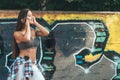 Beautiful woman listening to music on headphones on graffiti background