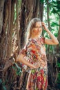 Beautiful woman with long blond hair poses on the background of trees. Portrait of a young long-haired girl Royalty Free Stock Photo