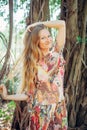 Beautiful woman with long blond hair poses on the background of trees. Portrait of a young long-haired girl Royalty Free Stock Photo