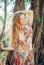 Beautiful woman with long blond hair poses on the background of trees. Portrait of a young long-haired girl