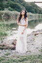 Beautiful woman with long curly hair dressed in boho style dress posing near lake Royalty Free Stock Photo