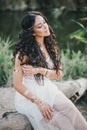 Beautiful woman with long curly hair dressed in boho style dress posing near lake Royalty Free Stock Photo