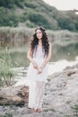 Beautiful woman with long curly hair dressed in boho style dress posing near lake Royalty Free Stock Photo