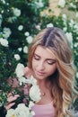 Beautiful woman with long curly hair smells white roses outdoors, closeup portrait of sensual girl face Royalty Free Stock Photo