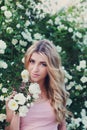 Beautiful woman with long curly hair smells white roses outdoors, closeup portrait of sensual girl face Royalty Free Stock Photo