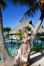 The beautiful woman in a long dress on the palm tree near the sea. Royalty Free Stock Photo