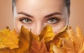 Beautiful woman with long eyelashes and with beautiful smokey eyes makeup holds yellow leaves near the face. Eyes close up.