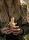 Beautiful woman with long hair holding flower. Hands with rings stylish boho accessories. No focus Royalty Free Stock Photo