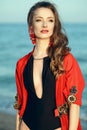 Beautiful woman standing at the seaside wearing trendy one piece halter neck swimsuit and red oriental beach cover up Royalty Free Stock Photo