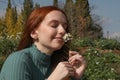 Beautiful woman with long hair smells a white flower with her eyes closed in a place full of flowers Royalty Free Stock Photo