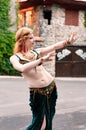 Woman with long hair in traditional green belly dance costume dancing in front of illuminated with sunlight buddhist temple