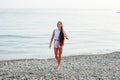 Beautiful tanned woman with long hair walks on the beach by the sea Royalty Free Stock Photo