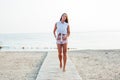 Beautiful tanned woman with long hair walks on the beach by the sea Royalty Free Stock Photo