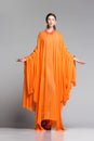 Beautiful woman in long orange dress posing dramatic in the studio Royalty Free Stock Photo