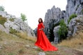 Beautiful woman in a long scarlet dress in a forest in the mountains Royalty Free Stock Photo