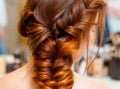 Beautiful woman with long red hair at the beauty salon, hairdresser braided a braid in a beauty salon. Professional hair care and Royalty Free Stock Photo