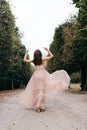 Beautiful woman in long rose evening dress walking path in park. Royalty Free Stock Photo